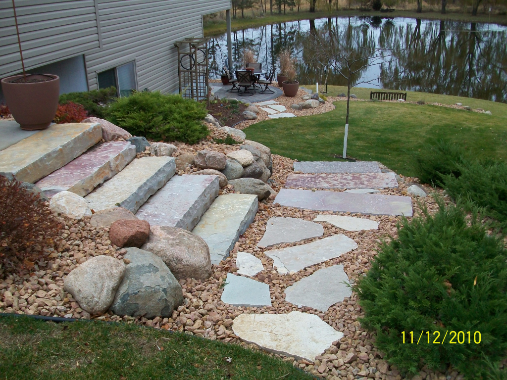 natural stone steps with flag stone steppers leading to a brick paver patio